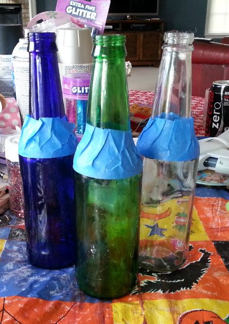 Empty Beer and Soda Glass Bottles Taped off waiting for glitter to be applied to be turned into vasees