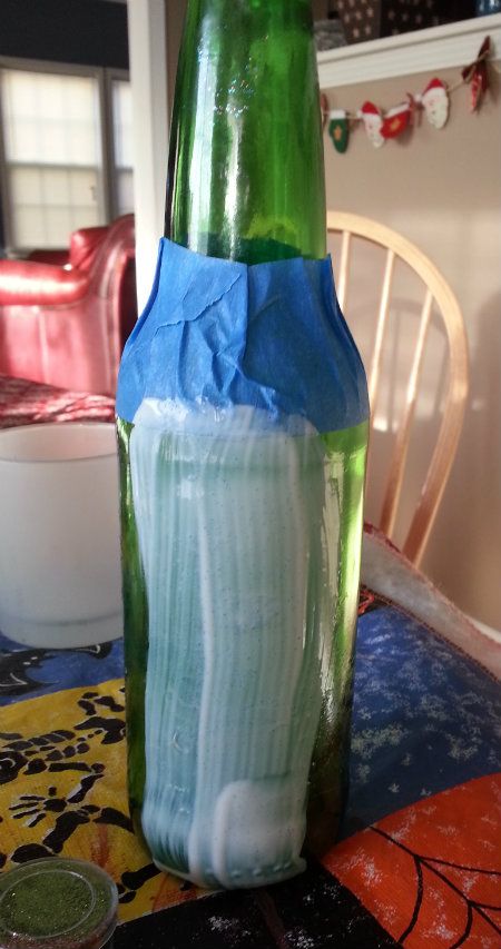 Glass Soda bottle taped off and coated in modge podge waiting for glitter to be put on to be turned into a vase